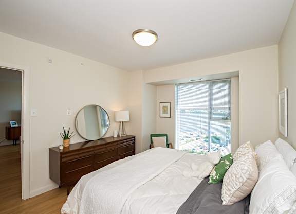 A bedroom with a large bed and a mirror on the dresser.