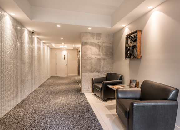 A hallway with a carpeted floor, a stone wall, and a framed picture on the wall.