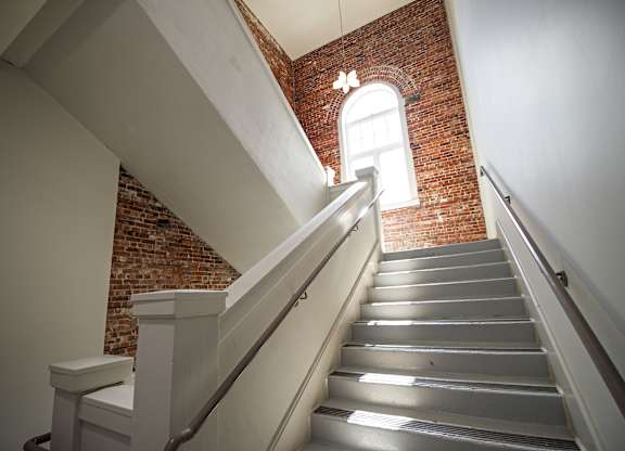 A staircase with a metal railing and a brick wall in the background.