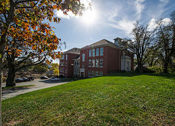 A red brick building with a green lawn in front.