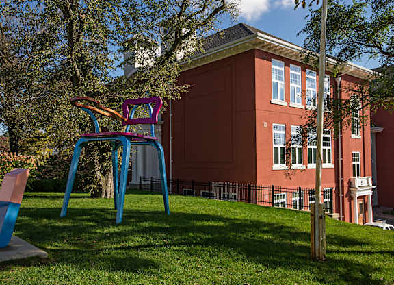 A playground with a blue and purple slide in front of a red building.