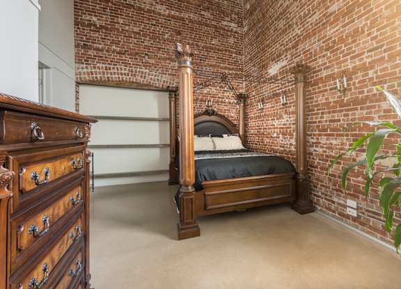 A bedroom with a brick wall and a bed.