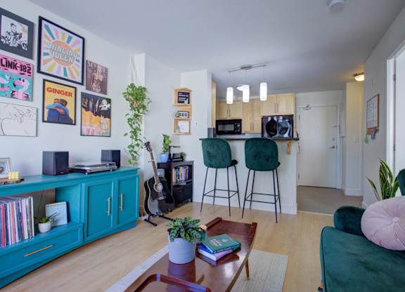 A living room with a green couch, a guitar, and a bookshelf.