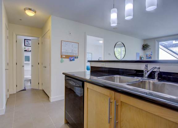 A kitchen with a sink, dishwasher, and refrigerator.