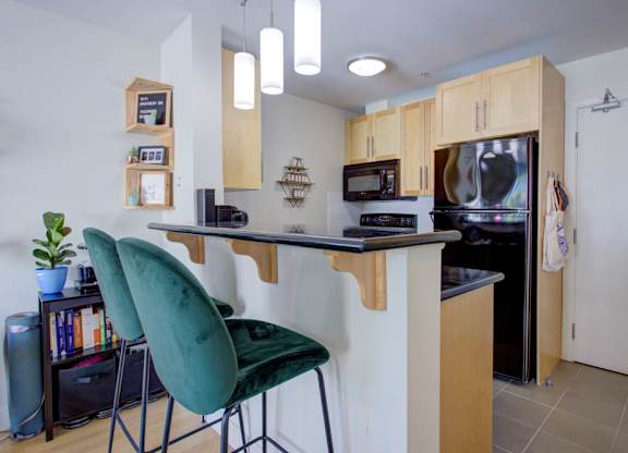 A kitchen with a green chair and a black countertop.