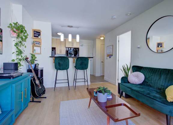 A living room with a green couch, a guitar, and a potted plant.