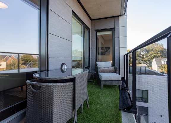 A balcony with a table and chairs overlooking a residential area.