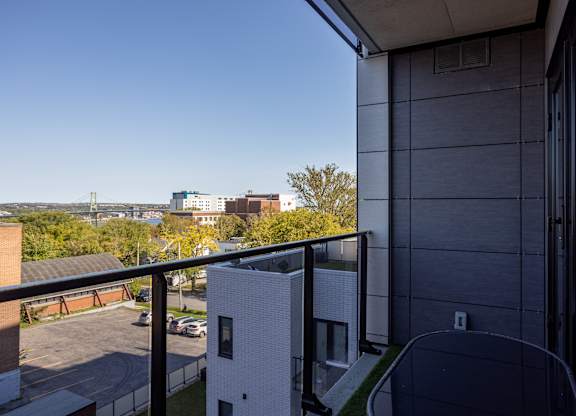A view from a balcony of a building with a white brick building in the distance.