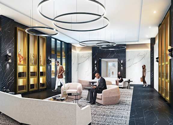 A man in a suit is sitting in a chair in a modern lobby.