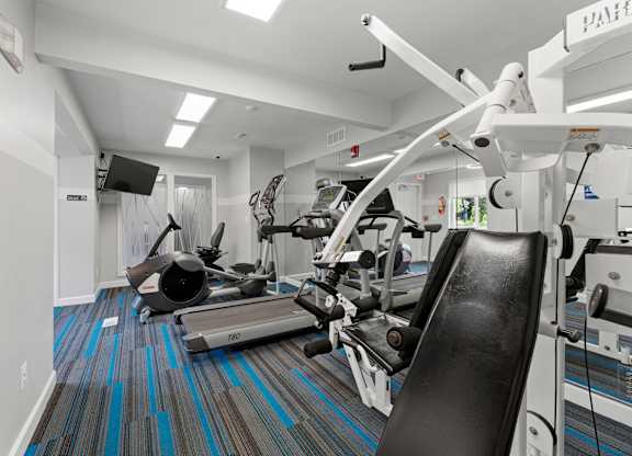 A gym with a variety of equipment including a treadmill, rowing machine and weights.