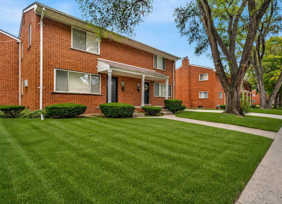 A red brick house with a green lawn in front.