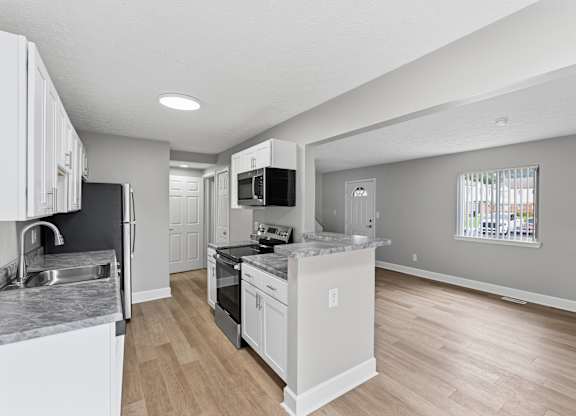A kitchen with white cabinets and a black countertop.