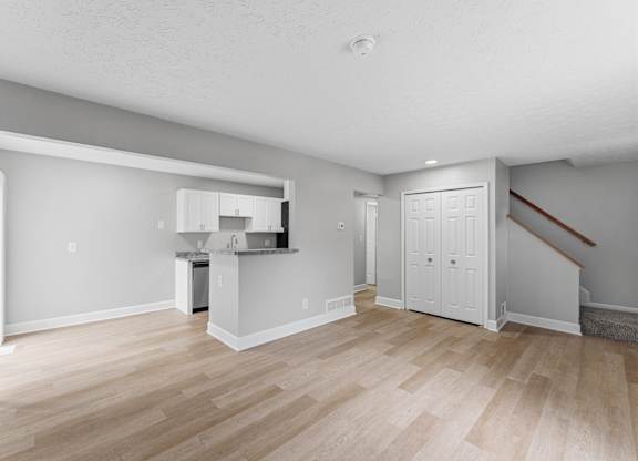 A spacious room with a kitchenette and a staircase.