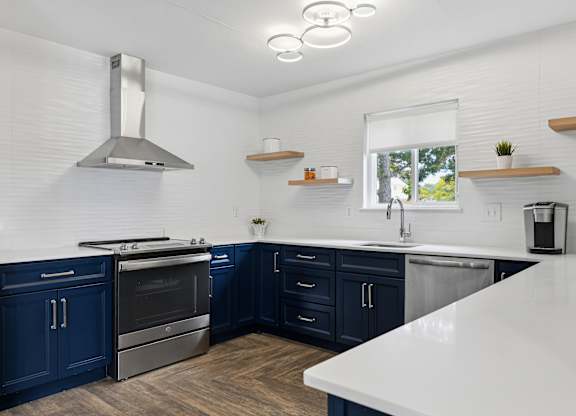A modern kitchen with dark blue cabinets and stainless steel appliances.