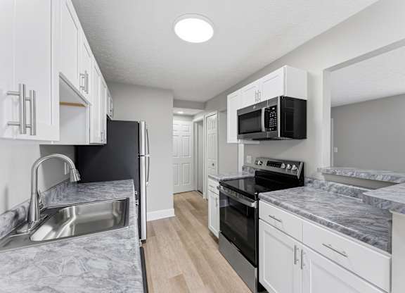 A kitchen with white cabinets and a marble countertop.