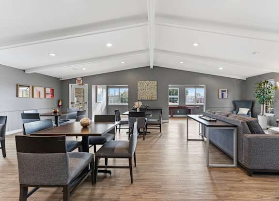 A modern living room with a wooden floor and grey furniture.