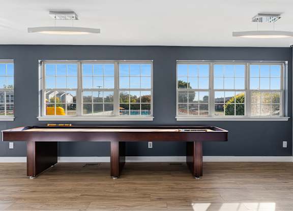 A room with a pool table and a view of the outside through the windows.