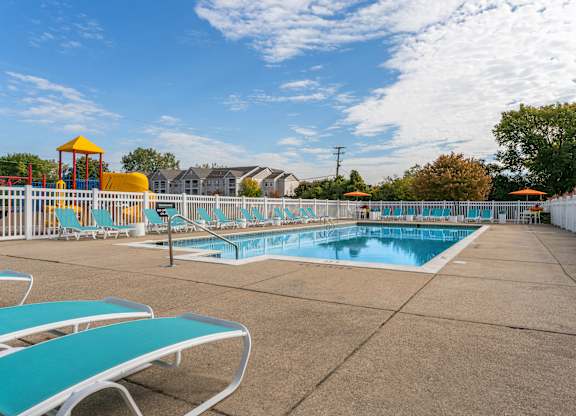 A sunny day at the pool with blue water and white lounge chairs.