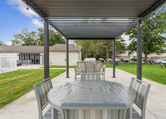 A grey table and chairs are set up under a metal roof.