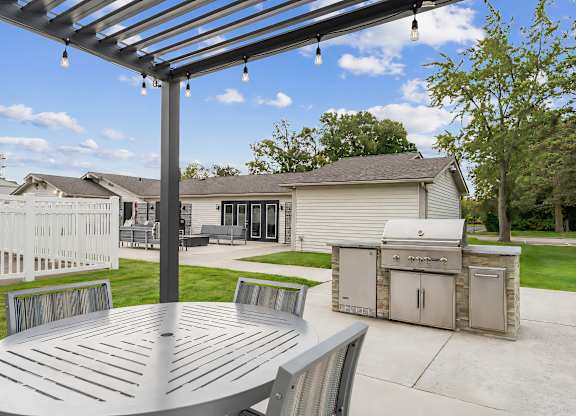 A patio with a table and chairs under a pergola.