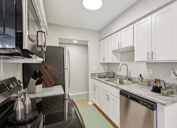 A kitchen with white cabinets and a black stove top.