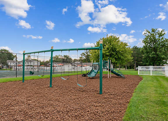 A playground with a green swing set and a green slide.