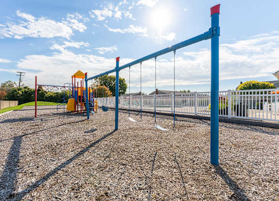A playground with a swing set and a blue pole.