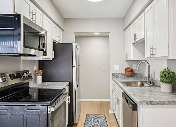 A kitchen with white cabinets and a black refrigerator.