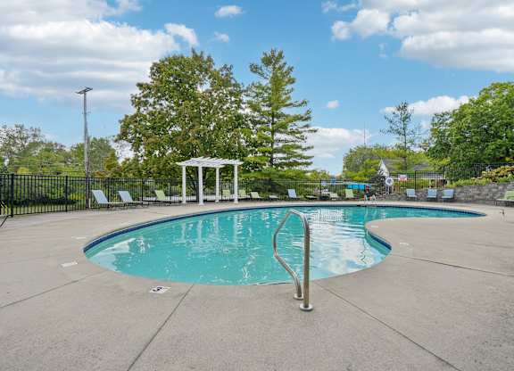 A pool with a diving board and a gazebo in the background.
