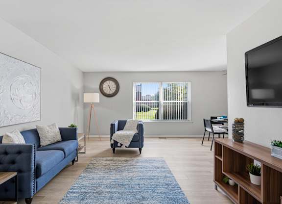 A living room with a blue couch and a wooden floor.