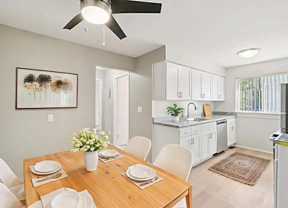 A dining room with a table set for two and a ceiling fan.