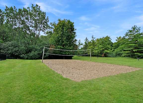 A volleyball net is set up in the middle of a grassy field.