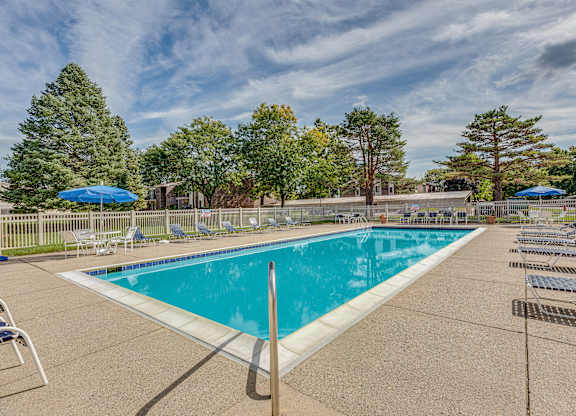 A large outdoor swimming pool surrounded by trees and lounge chairs.