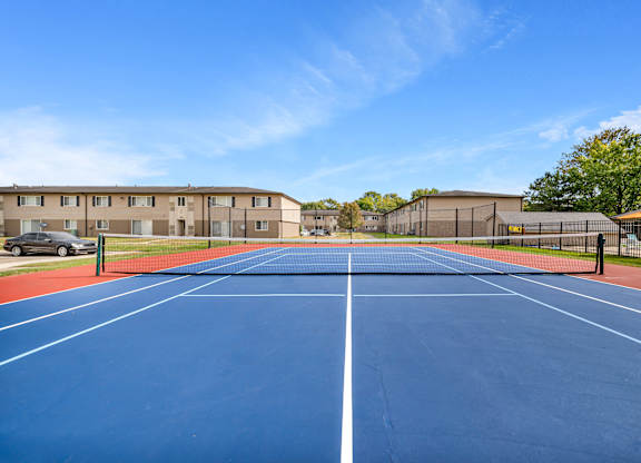 A blue tennis court with white lines and a fence in the background.