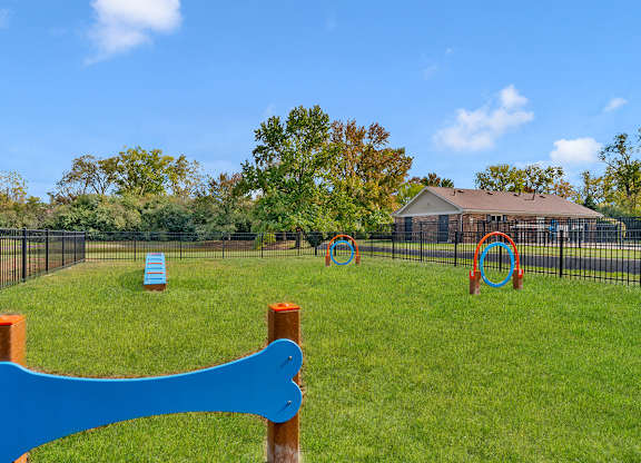 A dog park with a blue sign in the foreground.