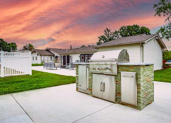 A backyard with a white fence and a stone and wood outdoor kitchen.