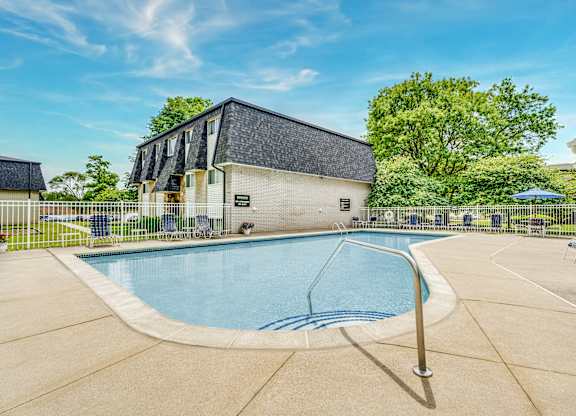 A swimming pool in a backyard with a building in the background.