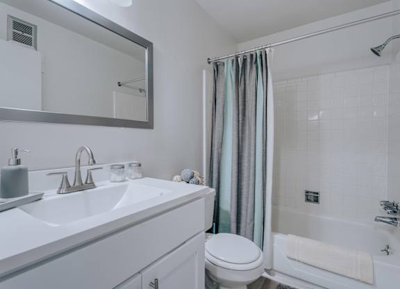 A white bathroom with a sink, toilet, and shower.