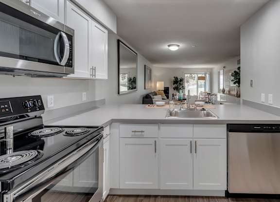 A modern kitchen with white cabinets and stainless steel appliances.