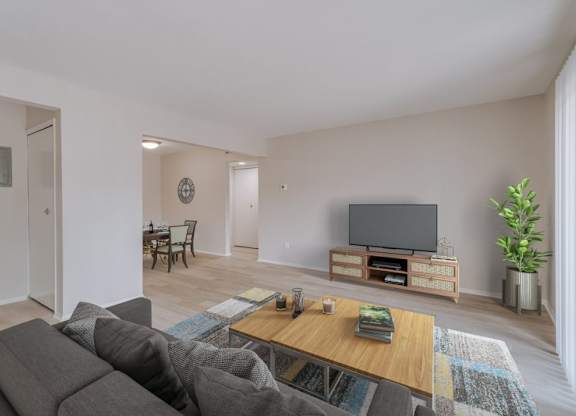 A living room with a grey couch, a wooden coffee table, and a flat screen TV.
