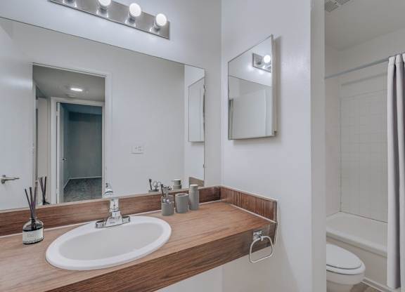 A bathroom with a sink, mirror, and toilet.