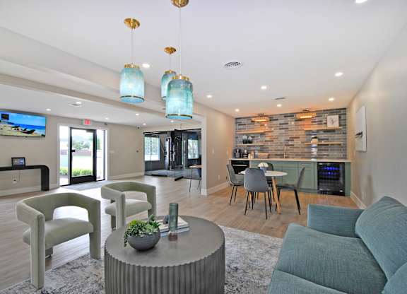 A modern living room with a grey sofa, a grey armchair, a grey coffee table, a grey rug, a grey wall, a grey fireplace, a grey dining table, a grey chair, a grey TV, a grey