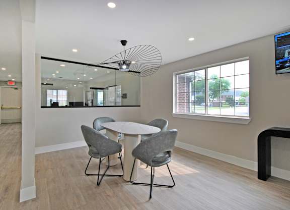A modern dining room with a round table and grey chairs.