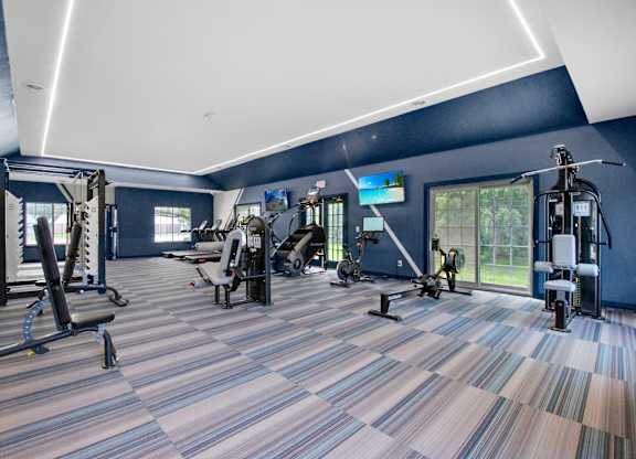 A gym with a variety of equipment including treadmills, weights, and exercise machines.
