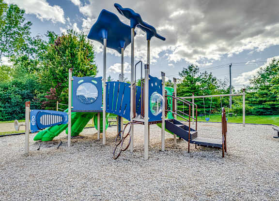 A playground with a blue slide, a green slide, and a wooden swing set.