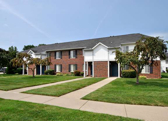 A brick house with a white roof and a tree in front.