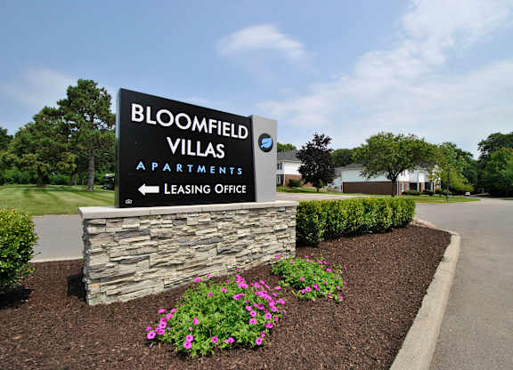 A sign for Bloomfield Villas Apartments with a leasing office.