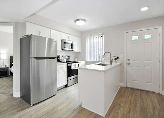 A modern kitchen with a stainless steel refrigerator and white cabinets.