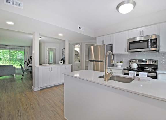 A modern kitchen with white cabinets and stainless steel appliances.