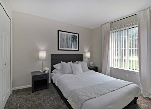 A bedroom with a large bed and a framed picture on the wall.